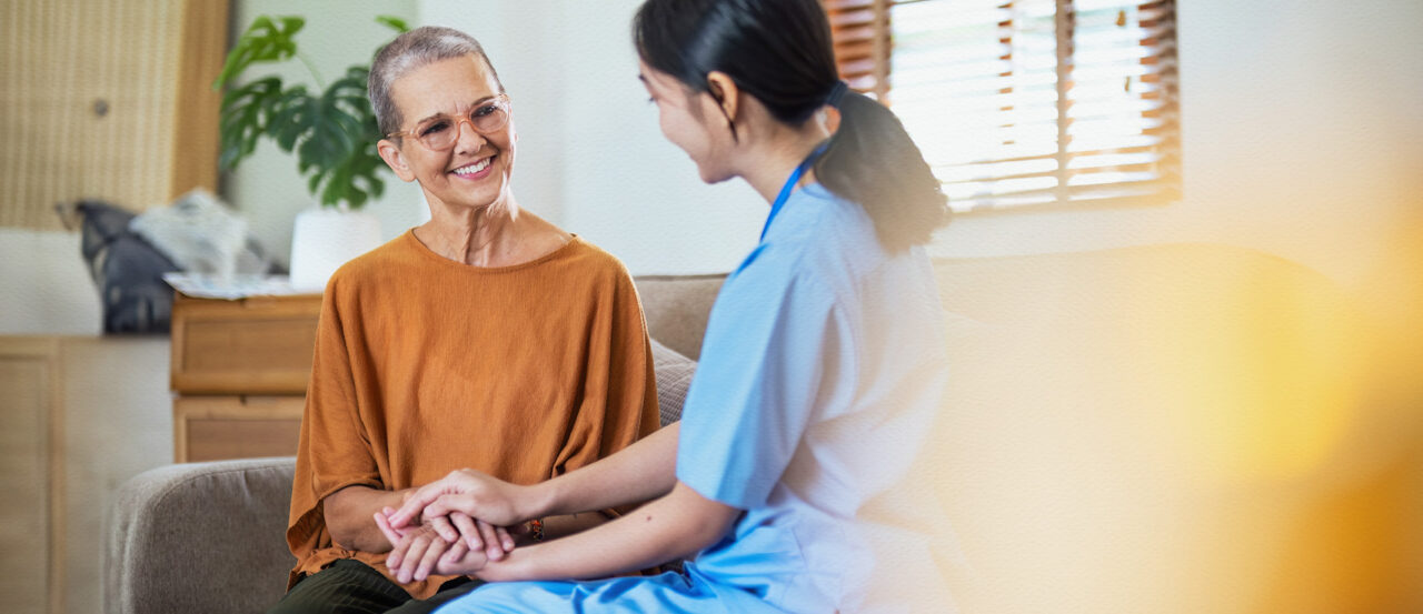 in-home aide holding hands with senior woman