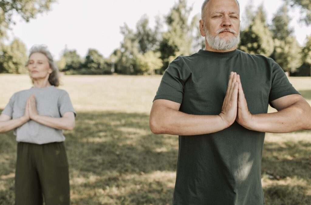 senior man and senior woman practicing yoga outdoors
